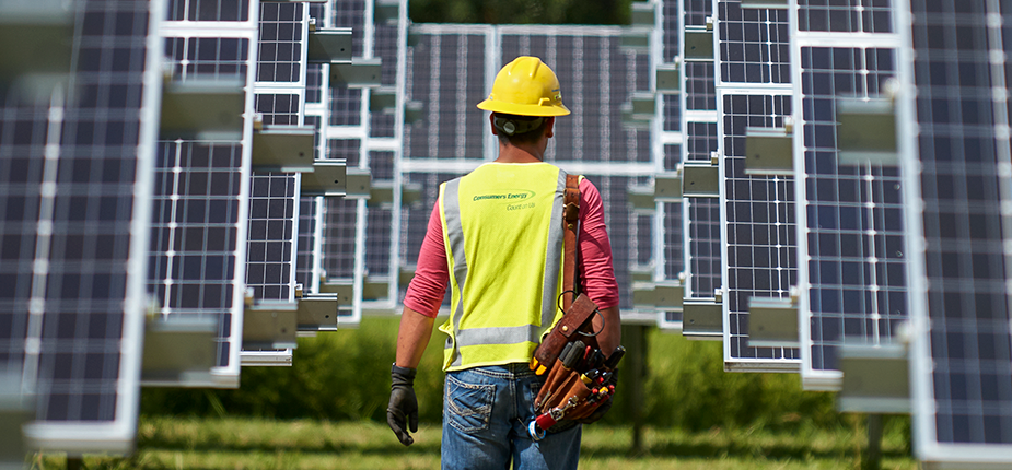 Consumers Energy field worker walking among an array of solar panels